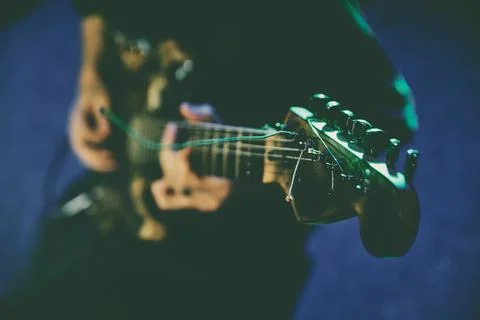 Electric guitar strings vibrating on dark stage under blue light 스톡 사진