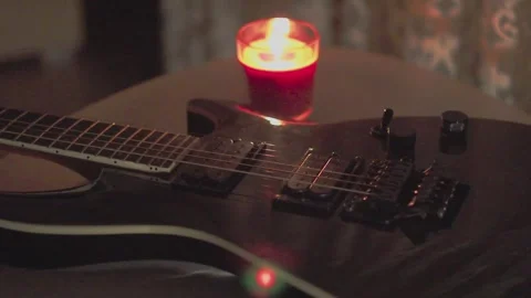 Electric guitar on table with burning candle in cozy dark atmosphere Video stock 338180836
