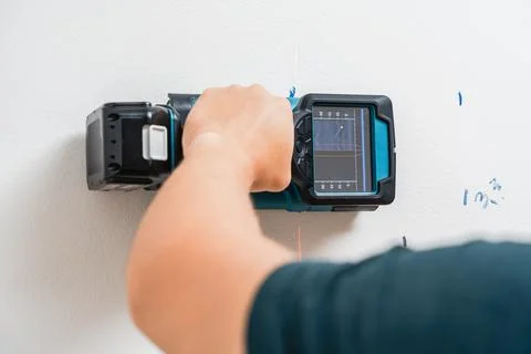 Electric Hand Using Digital Stud Finder Detecting Wires in Wall Foto stock
