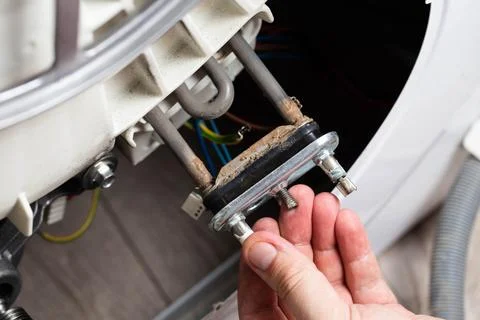 Electric heating element in hand against the background of a washing machine 写真素材