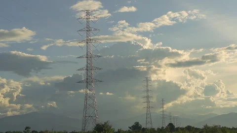 Electric high voltage towers with timelapse moving clouds Stockbeeldmateriaal 337639678