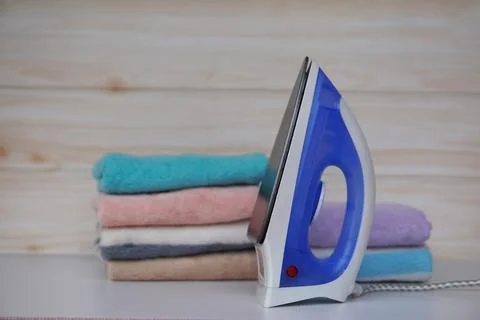 Electric iron and stack of folded clothes Stock Photos