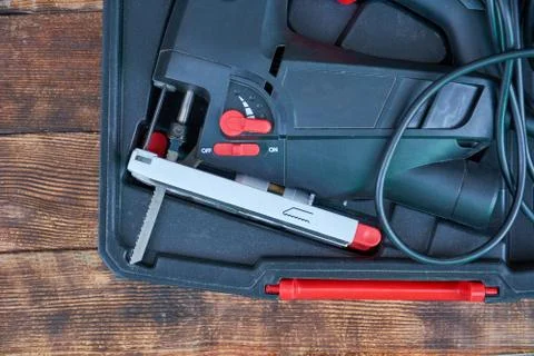 Electric jigsaw in plastic case on dark rustic wooden background. Electric to Stock Photos