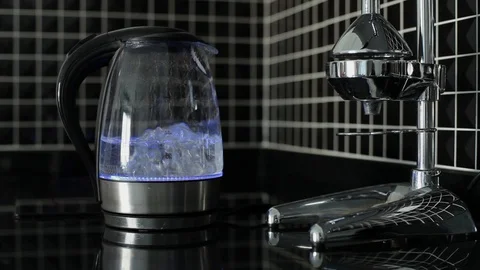 Electric kettle with blue highlight is boiling. Woman hand takes off teapot Stock Footage 115860032