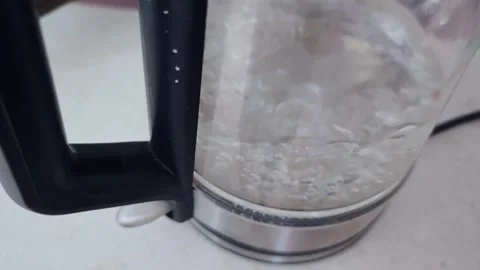 Electric kettle boiling water with visible bubbles forming and rising inside the Stock Footage 334324379