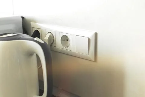 Electric kettle cable in power socket in modern kitchen interior Stock Photos