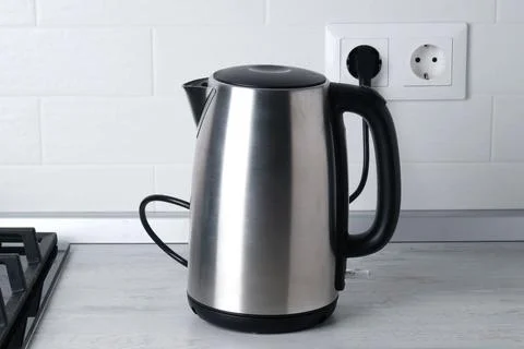 Electric kettle on the kitchen table against the background of white shingle Fotos de archivo