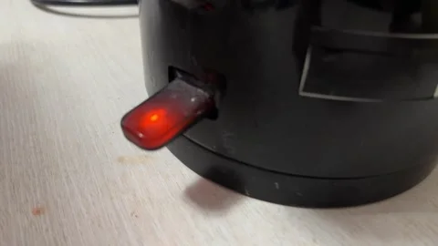 Electric kettle power button with glowing red indicator light, kitchen appliance Stock Footage 337117881