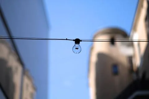 Electric light bulb on the cable between the houses Stock Photos