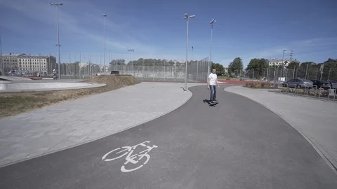Electric Longboard man in white t-shirt and hat ride on red sport stadium with Stock-Footage 90814726