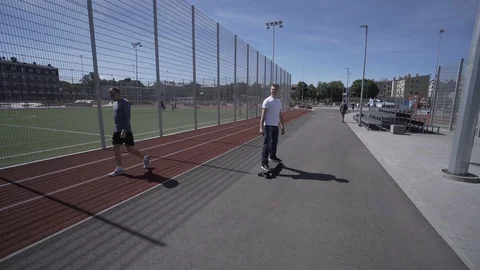 Electric Longboard man in white t-shirt and hat ride on red sport stadium with 動画素材 90815048