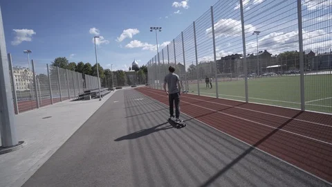 Electric Longboard summer ride on red sport stadium with playground Видео 90808711