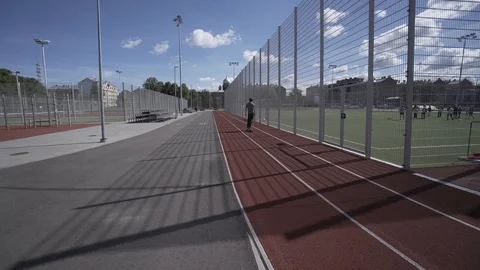 Electric Longboard summer ride on red sport stadium with playground Stock-Footage 90809406