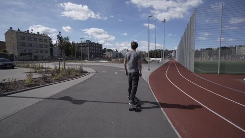 Electric Longboard summer ride on red sport stadium with playground 動画素材 90809543