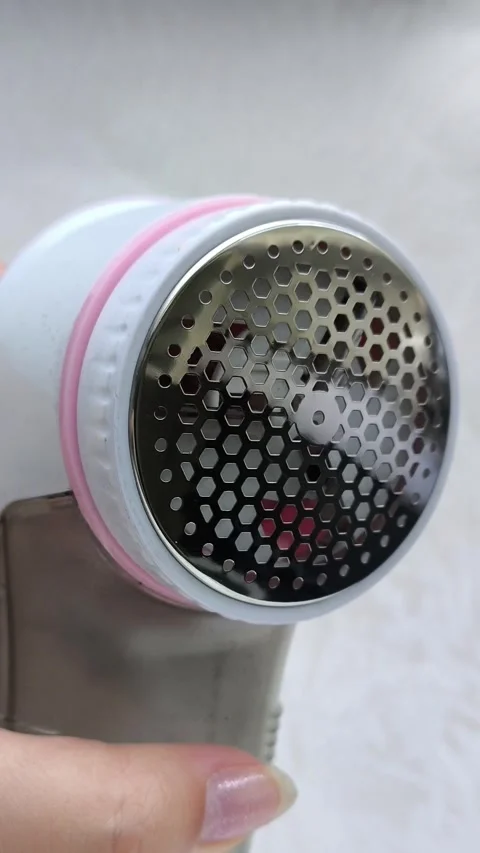 An electric machine for removing lint, pellets from clothes in a womans hand Stock Footage 316200951