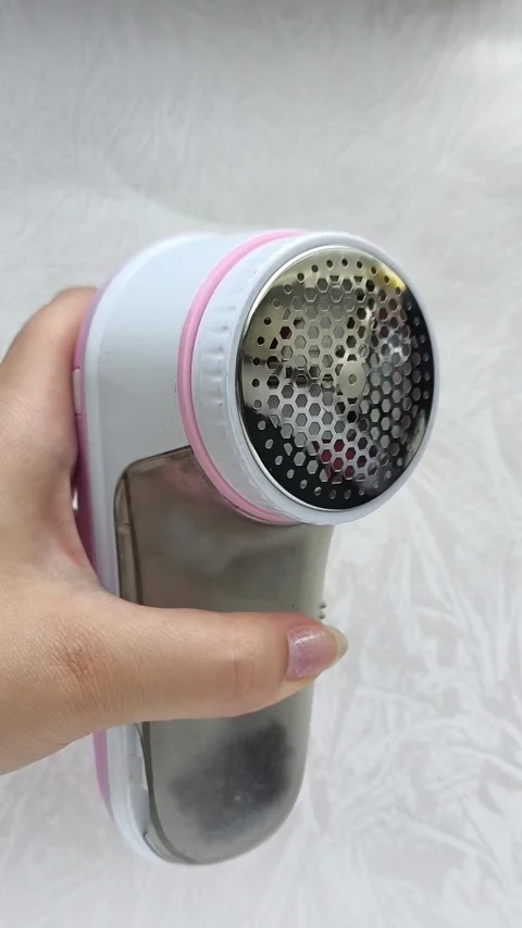 An electric machine for removing lint, pellets from clothes in a womans hand Stock Footage 316201016