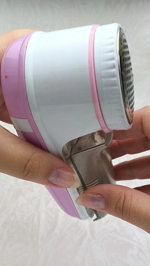 An electric machine for removing lint, pellets from clothes in a womans hand Stock Footage 316201236