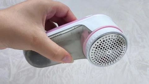 An electric machine for removing lint, pellets from clothes in a womans hand Video stock 316203031