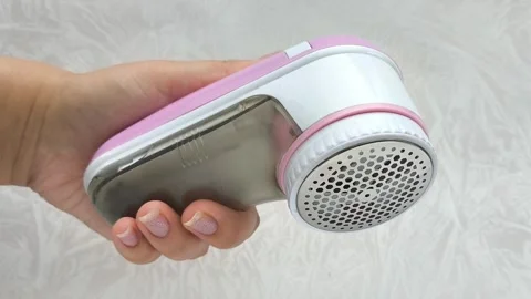 An electric machine for removing lint, pellets from clothes in a womans hand Stock Footage 316203236