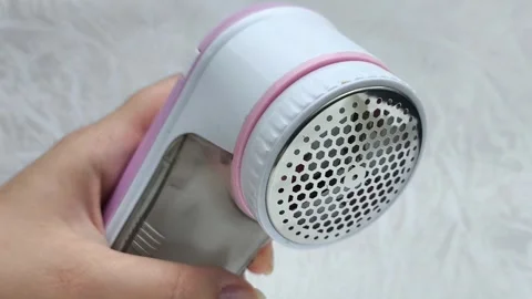 An electric machine for removing lint, pellets from clothes in a womans hand Stock Footage 316203619