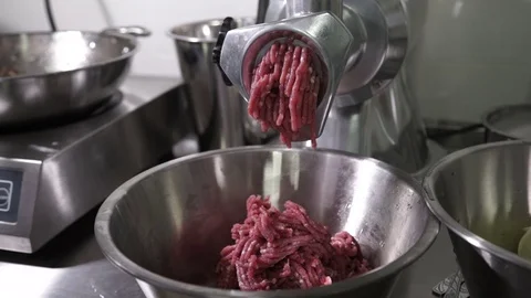 Electric meat grinder of metal scrolls red meat in the kitchen cafe Stock Footage 71531544