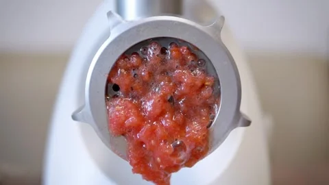 Electric meat grinder processing red tomatoes into juice close up 動画素材 330117879