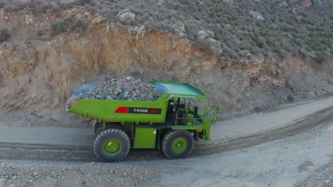 Electric mining dump truck carrying rock on a quarry road. aerial Stock Footage 332480101