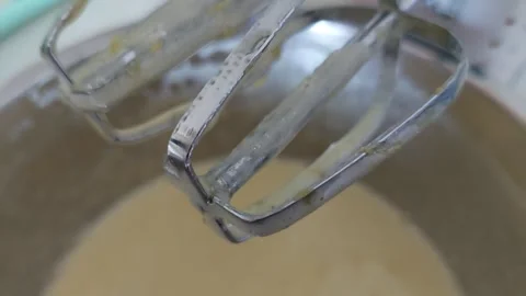 Electric mixer beaters with cake batter over metal bowl close up Stock Footage 334328448