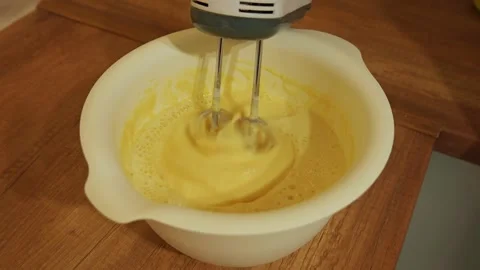 Electric mixer beating eggs and flour for cake batter Stockbeeldmateriaal 334685391
