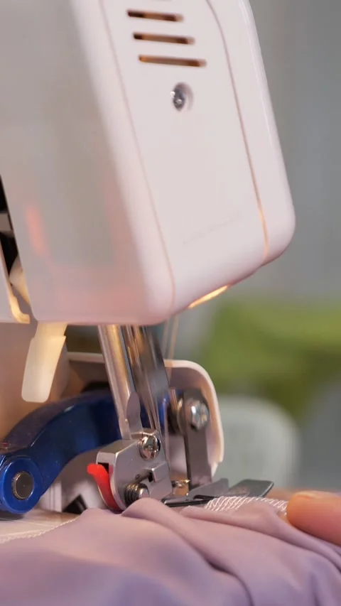 Electric overlocker sewing machine stitching delicate lilac fabric, showcasing Video stock 341446228