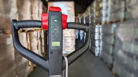 Electric pallet jack with control panel in a warehouse, surrounded by stack Stock Photos