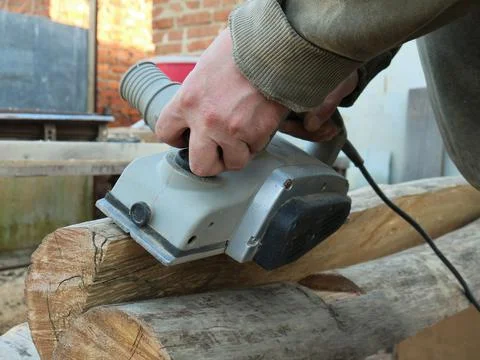 Electric planer processes the surface of the log Stock Photos