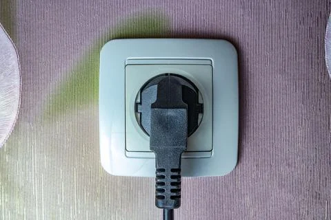 The electric plug is plugged into a wall outlet Stock Photos