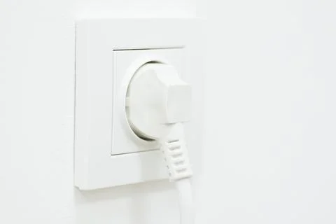 Electric plug in rosette on white wall, copy space Stock Photos
