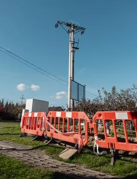 An electric pole behind a red protective fence - a protective band at earth.. Stock Photos