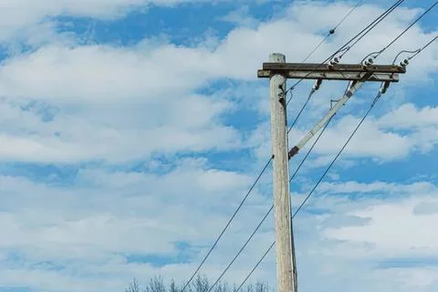 Electric pole with power lines under blue sky and clouds Stock Photos