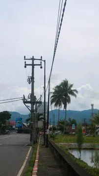 Electric pole by the roadside with overcast clouds Stock Photos