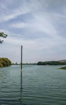 A electric pole in a water pond with reflection of it in a blue water Stock Photos