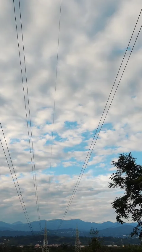 Electric power poles against the backdrop of the Alpine mountains. Clouds at Stock Footage 308805610