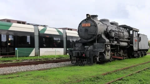 The electric rail train overtaking the steam locomotive in Railway Cultural Park Video stock 259694173