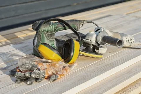 Electric sander, angle grinder and personal protective equipment on wooden bo Stock Photos
