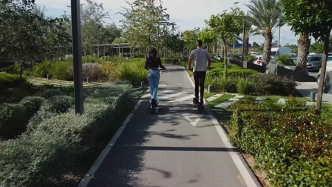 Electric scooters. Drone sequence shot. Follow-up of a boy and girl couple wh Stock Footage 220879885