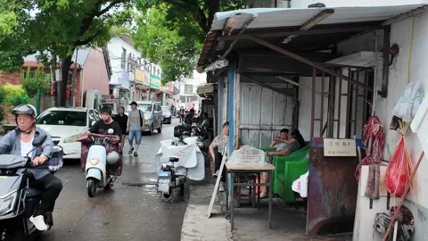 Electric Scooters Pass Through a Rainy Shanghai Market Lane Stock Footage 340176816