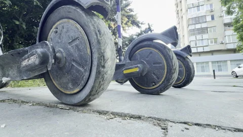 Electric scooters stand parked in a row on a city sidewalk Stock Footage 336936960