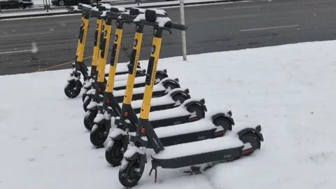 Electric scooters under the snow during a snowfall Stock Footage 224815230