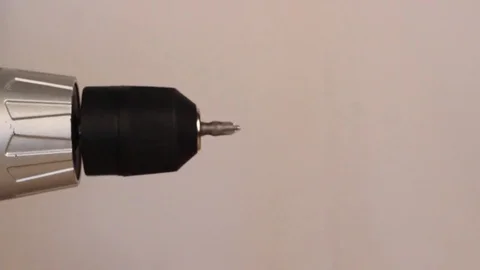 Electric screwdriver in hand at white desk background Stock Footage 75149489