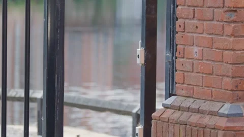 Electric Security Gate Closing Against Brick Wall in Urban Setting Stock Footage 316273176