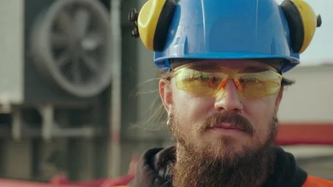 Electric station worker with long beard stands against fan Stock Footage 143079040