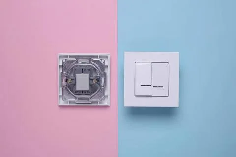 Electric switch and socket on pastel pink and blue wall Stock Photos