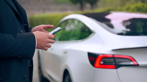 Electric Tesla car on drive test, man using smartphone for autopilot function Video stock 163930787